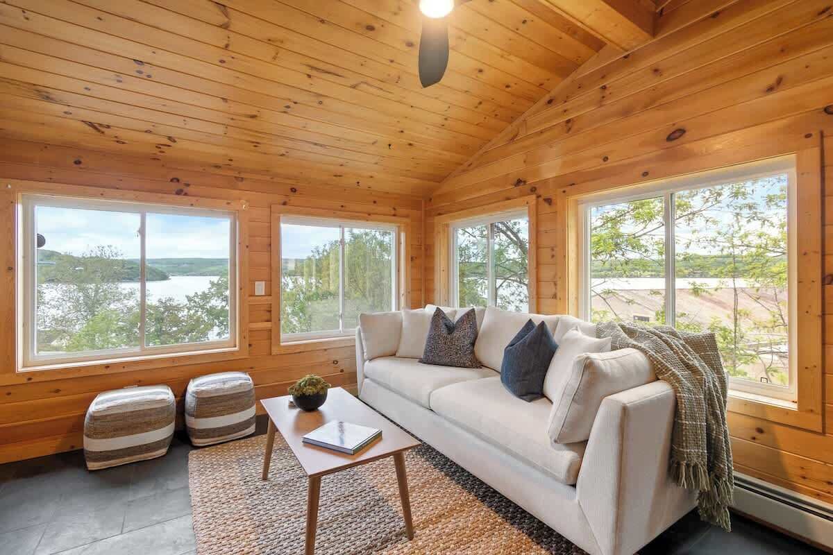 Ein gemütliches Blockhaus-Interieur mit einer Couch, Poufs und einem Couchtisch.