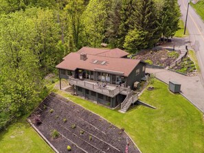 Ein zweistöckiges Haus mit Balkon, umgeben von einem gepflegten Rasen und Bäumen.