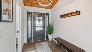 A hallway with a wooden ceiling, a bench, a coat rack, and a potted plant. - Lakeview House: Hot Tub, Speakeasy, Firepit, Gameroom (Hammondsport)