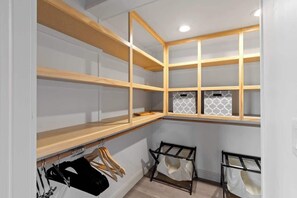A corner closet with open shelving, a hanging rack, and a shoe rack. - Lakeview House: Hot Tub, Speakeasy, Firepit, Gameroom (Hammondsport)