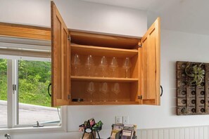 Un armario de madera con copas de vino, una ventana y un adorno en la pared.