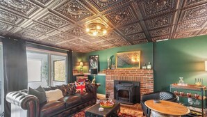 A living room with a leather sofa, a fireplace, a wooden coffee table, and a patterned rug. - Lakeview House: Hot Tub, Speakeasy, Firepit, Gameroom (Hammondsport)