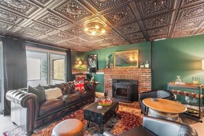 Ein Wohnzimmer mit Ledersofa, Kamin, Holz-Couchtisch und einem gemusterten Teppich.