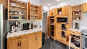 A kitchen with wooden cabinets, a microwave, a coffee maker, and a stove. - Lakeview House: Hot Tub, Speakeasy, Firepit, Gameroom (Hammondsport)