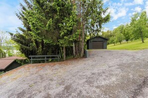A gravel driveway leading to a wooden structure, surrounded by trees and a grassy area. - Lakeview House: Hot Tub, Speakeasy, Firepit, Gameroom (Hammondsport)