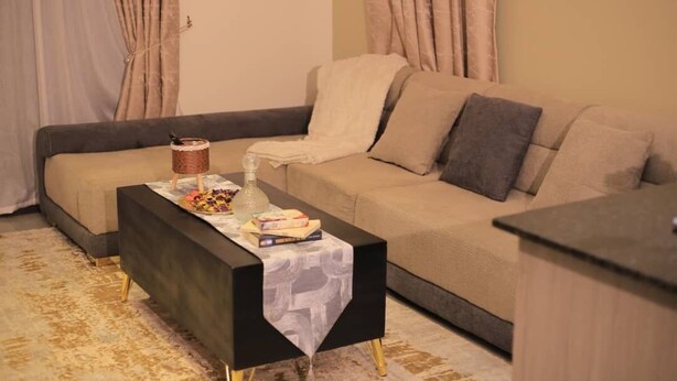 A living room with a sofa, a coffee table, and a small side table. - NJ Homes Bunga  (Kampala)