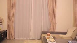 A living room with a sofa, a coffee table, and curtains. - NJ Homes Bunga  (Kampala)
