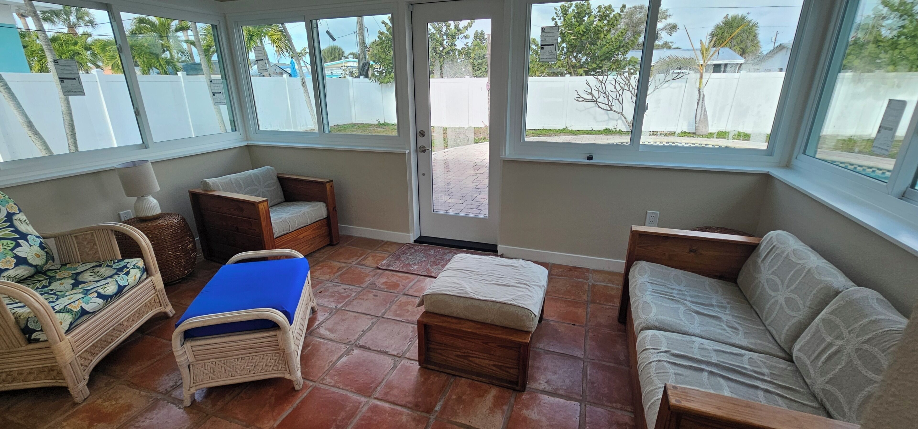 A sunroom with wicker furniture, a bench, and a view of the outside.