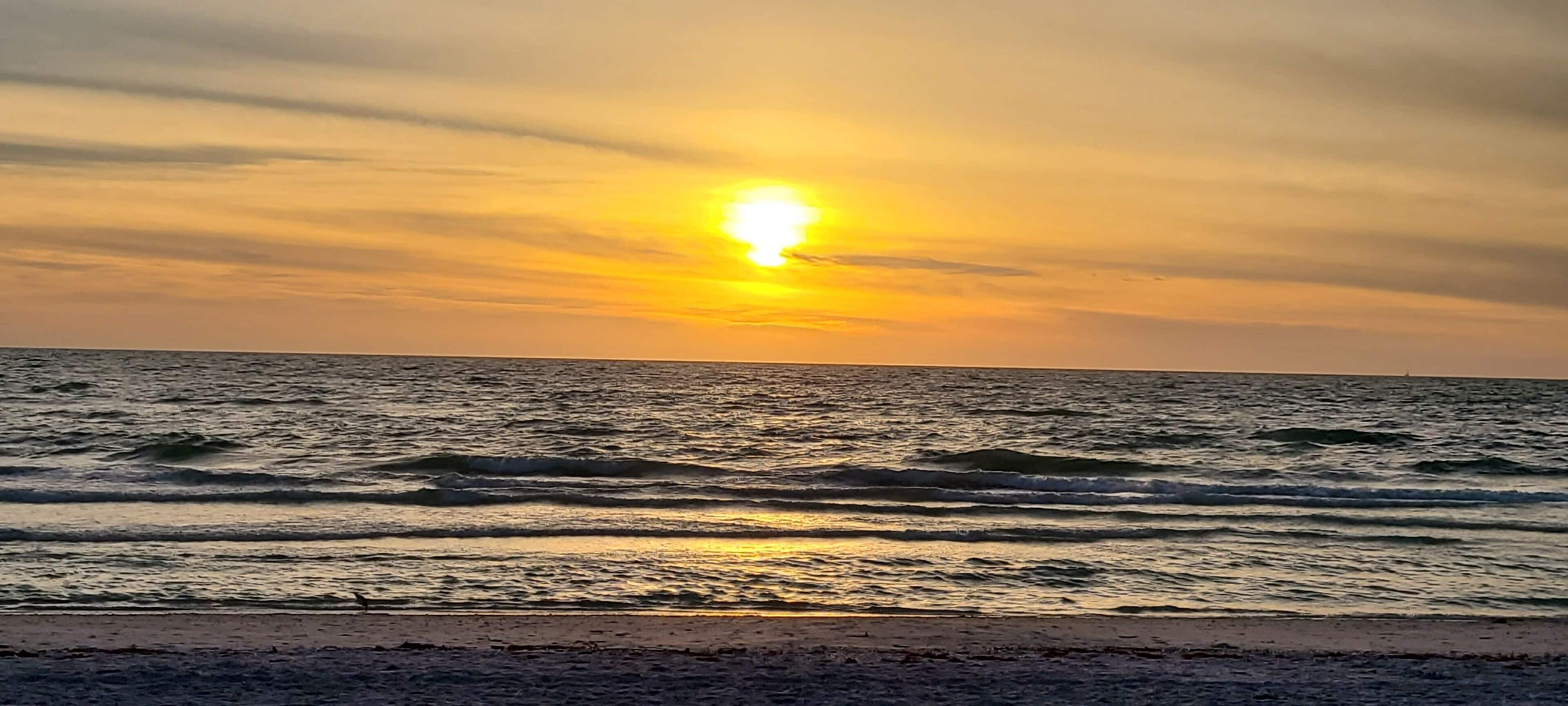A sunset over the ocean with waves.