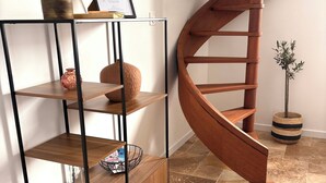 A wooden spiral staircase, a metal shelving unit with a vase and a framed certificate, and a small potted plant. - Le Mocopek Vacation Rental (sleeps 5) (Bolbec)