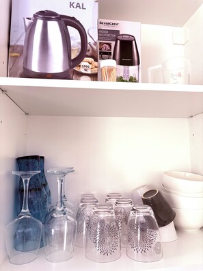 A kitchen shelf with a kettle, a coffee maker, and a box of kitchen tools. Below, there are wine glasses and a vase. - Le Mocopek Vacation Rental (sleeps 5) (Bolbec)