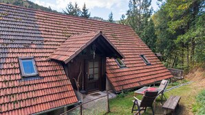 A rustic cabin with a sloped roof, a small porch, and a table with chairs outside.