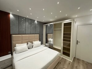 A modern bedroom with a large bed, a walk-in closet, and built-in cabinets. - Lovely 1-Bedroom Apartment in Lekki 1 with Fast Wi-Fi & 24/7 Power (Lagos)