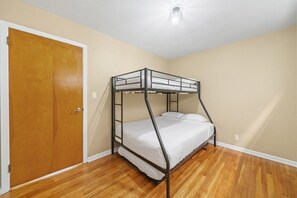 A bunk bed in a room with wooden flooring and a door. - Near NYC Duplex | PS5 + Gym | Sleeps 11 (Bayonne)