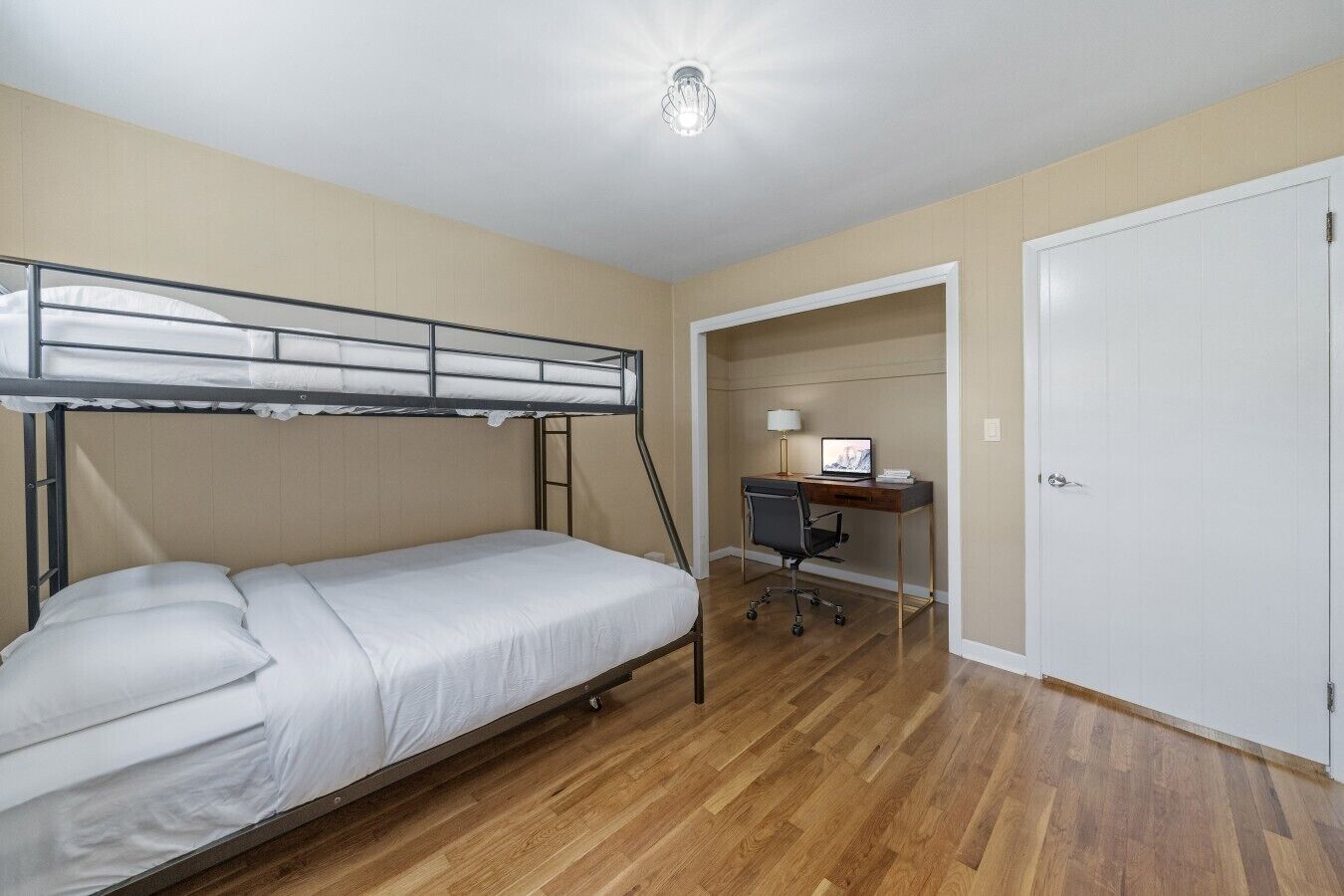 Eenpersoonskamer met een stapelbed, een bureau met stoel en een deur.