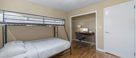 Une chambre individuelle avec un lit superposé, un bureau avec une chaise et une porte.