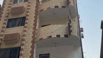 Un edifici residencial de diversos pisos amb balcons, antenes parabòliques i un cel serè.