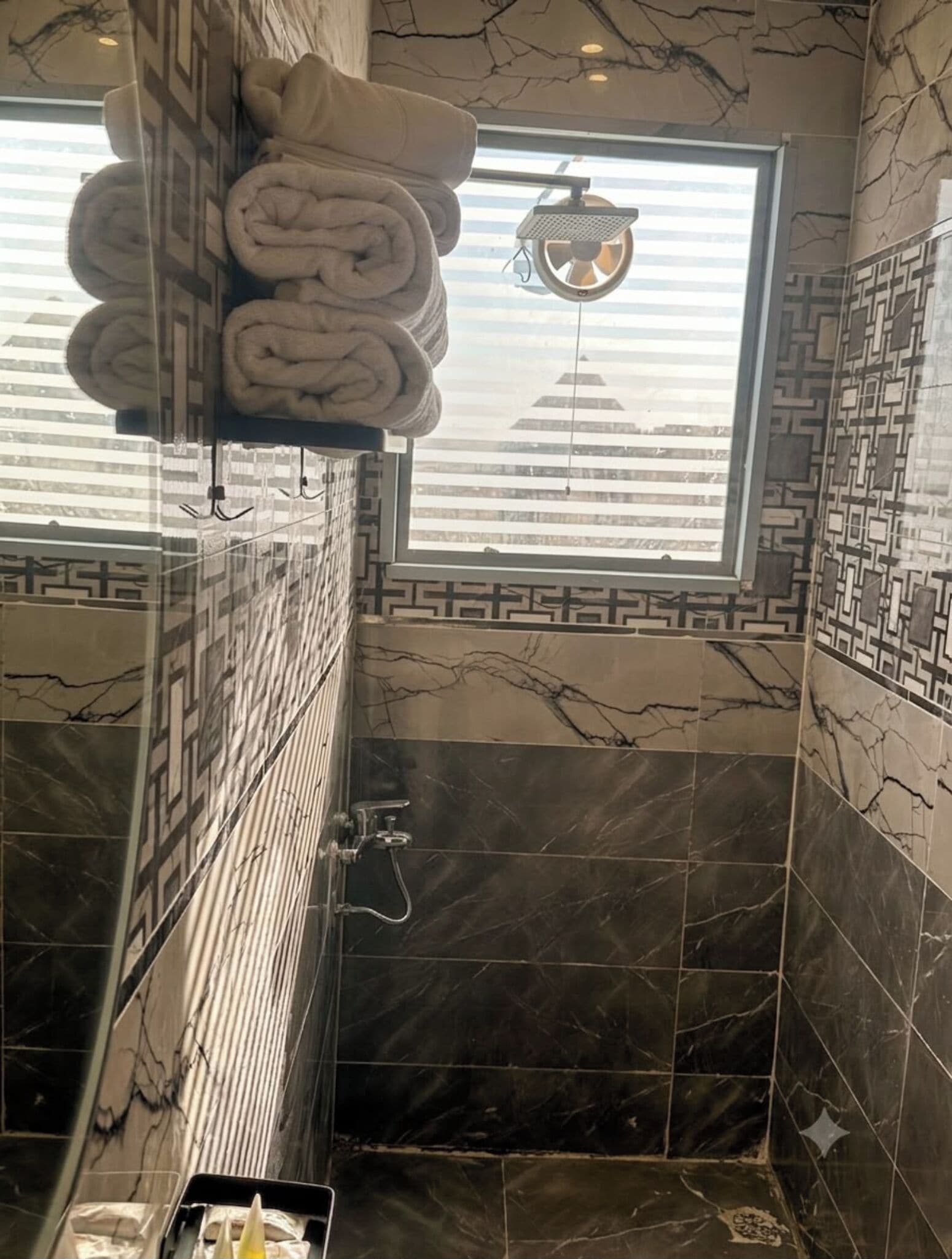 Un baño con ducha, toallero y ventana con vistas.