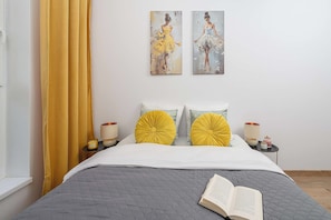 A neatly made bed with a book on it, two bedside lamps, and a window with curtains. - Ground-floor Apartment Stay With Garden Terrace (Łódź)