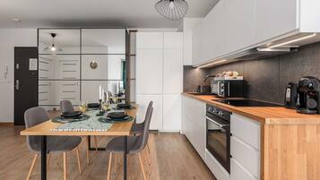 A modern kitchen with a wooden countertop, built-in oven, and a coffee machine.
