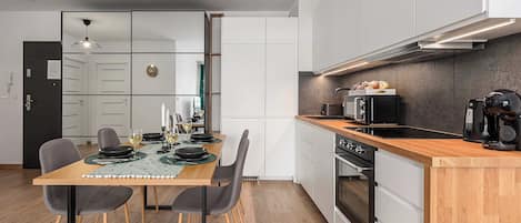 Una cocina moderna con encimera de madera, horno empotrado y cafetera.