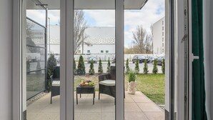 A sliding glass door leading to an outdoor patio area with a table, chairs, and a small garden.