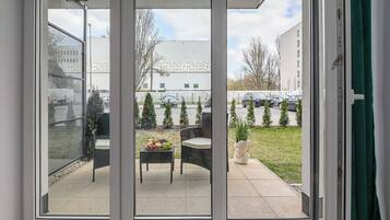 Een glazen schuifdeur die leidt naar een terras met een tafel, stoelen en een kleine tuin.