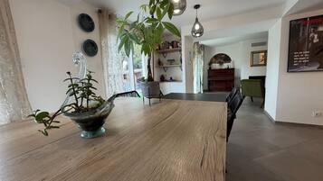 A dining area with a wooden table, a potted plant, and hanging pendant lights.