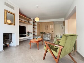 A living room with a television, a fireplace, a green armchair, and a wooden coffee table. - Charming Villa for 6 in Agde (Agde)