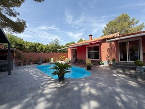A residential property with a swimming pool, patio furniture, and a red building with large windows. - Charming Villa for 6 in Agde (Agde)