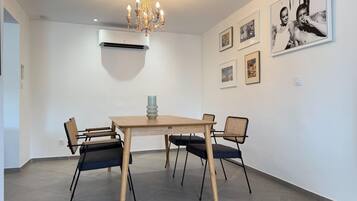 A dining area with a chandelier, air conditioning unit, and framed pictures on the wall.