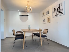 A dining area with a chandelier, air conditioning unit, and framed pictures on the wall. - Charming Villa for 6 in Agde (Agde)