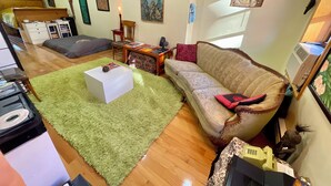 A room with a green rug, a sofa, a small table, and a bed. - GORGEOUS HUGE LOFT in the LES/CHINATOWN! (New York)