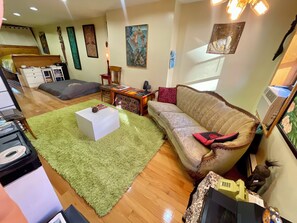 Ein Zimmer mit einem grünen Teppich, einem Sofa, einem kleinen Tisch und einem Bett.