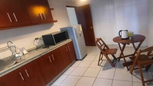 Une cuisine compacte équipée d’un four à micro-ondes, d’un réfrigérateur et d’une petite table à manger avec des chaises.