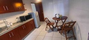 A compact kitchen with a microwave, refrigerator, and a small dining table with chairs. - Spacious, comfortable 2-bedroom apartment, Sopocachi - La Paz, Bolivia (La Paz)