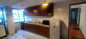 A kitchen with wooden cabinets, a microwave, and a sink. - Spacious, comfortable 2-bedroom apartment, Sopocachi - La Paz, Bolivia (La Paz)