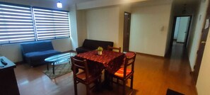 A dining area with a table and chairs, a sofa, and a window with blinds. - Spacious, comfortable 2-bedroom apartment, Sopocachi - La Paz, Bolivia (La Paz)