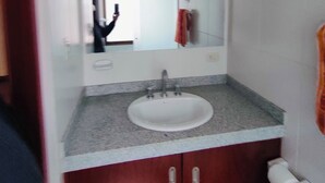 Une salle de bain avec un lavabo blanc, un miroir et une serviette accrochée au mur.