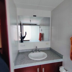A bathroom with a white sink, a mirror, and a towel hanging on the wall. - Spacious, comfortable 2-bedroom apartment, Sopocachi - La Paz, Bolivia (La Paz)