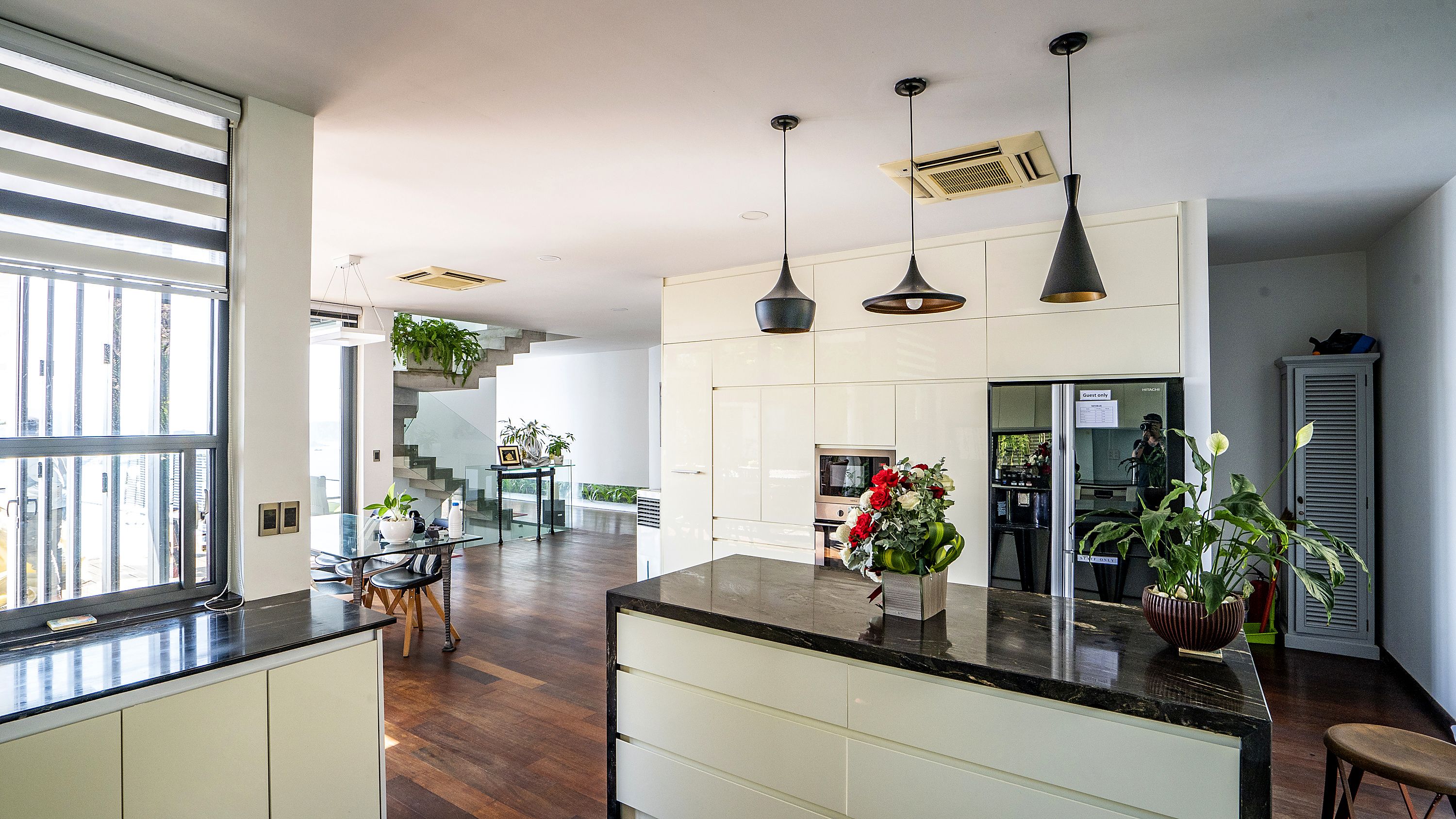 A modern kitchen with a central island, pendant lighting, and a view of a staircase leading to an upper level. - Koaniva Villa Ocean Beachfront Nha Trang (Nam Nha Trang)