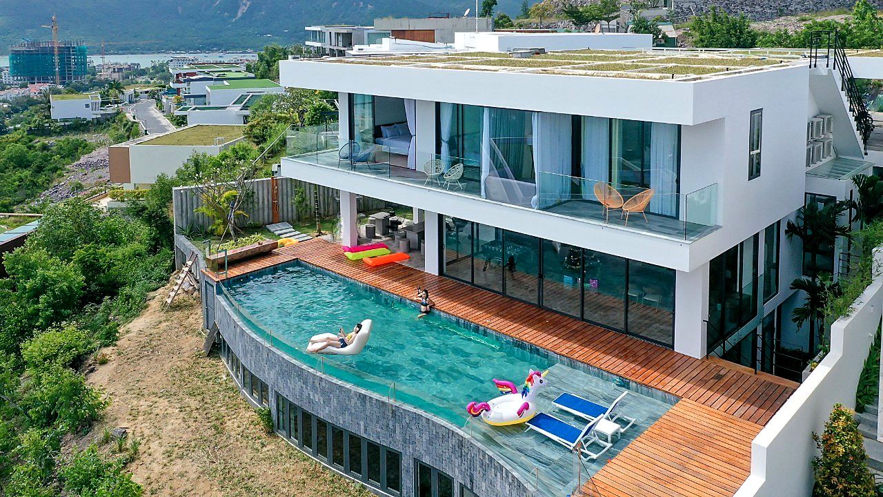 Una moderna casa a due piani con giardino pensile, piscina e balcone vetrato.