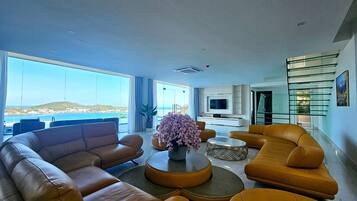 A modern living room with leather sofas, a coffee table, and a view of the sea.
