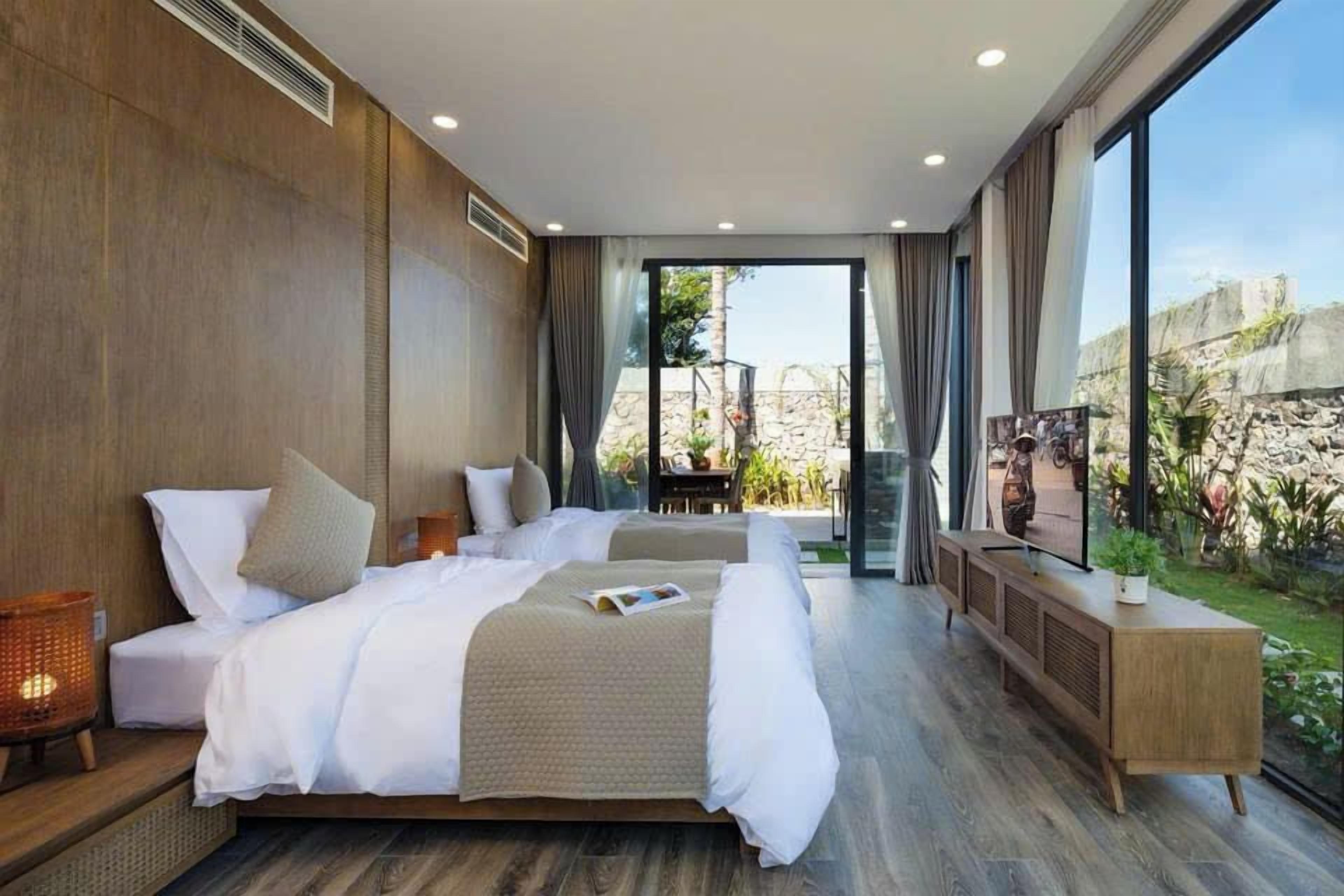 Una camera d'albergo moderna con un letto grande, una televisione e vista sull'esterno.
