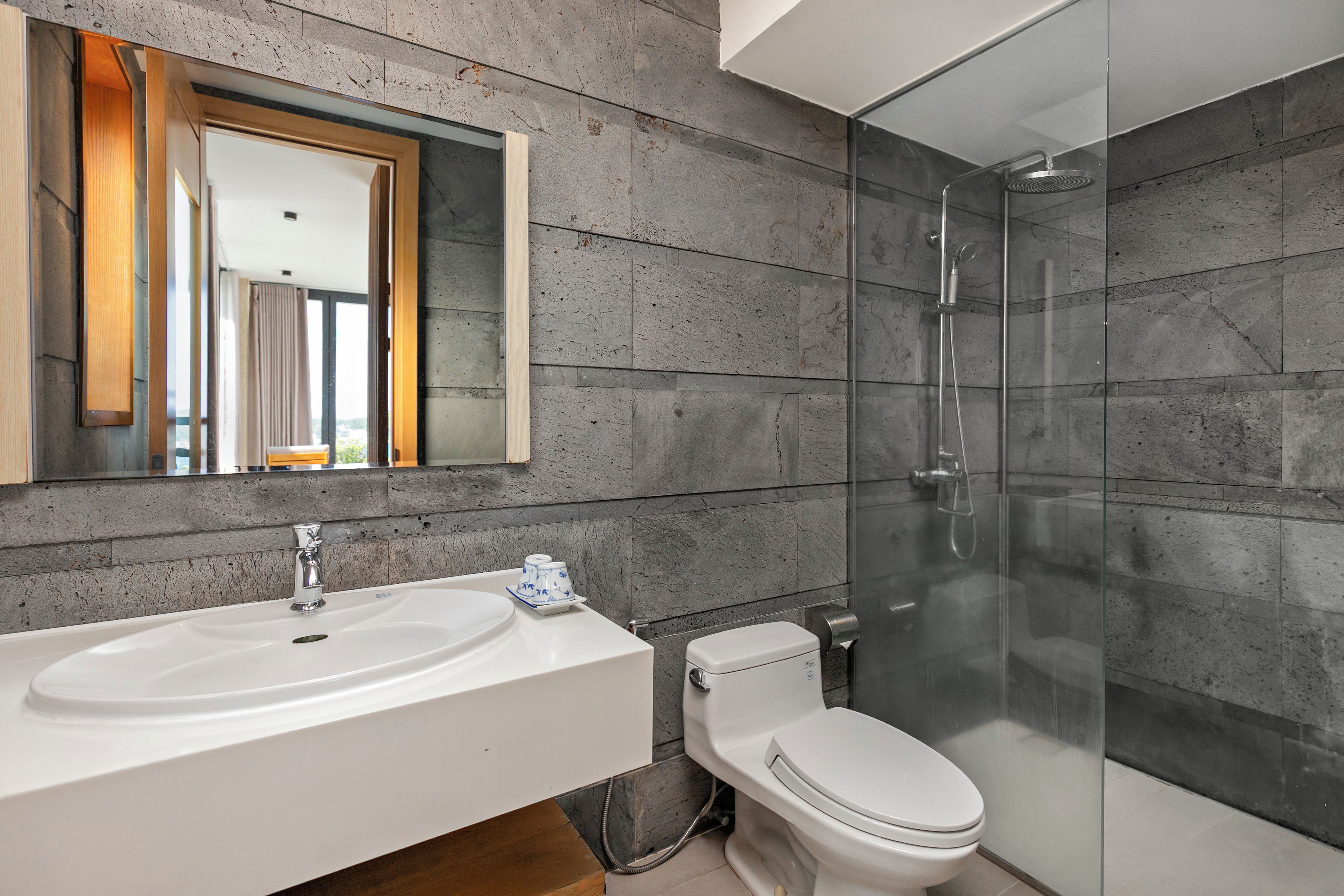 Un baño moderno con un lavamanos grande, inodoro y ducha con mampara de vidrio.