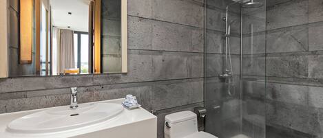 Un baño moderno con un lavamanos grande, inodoro y ducha con mampara de vidrio.