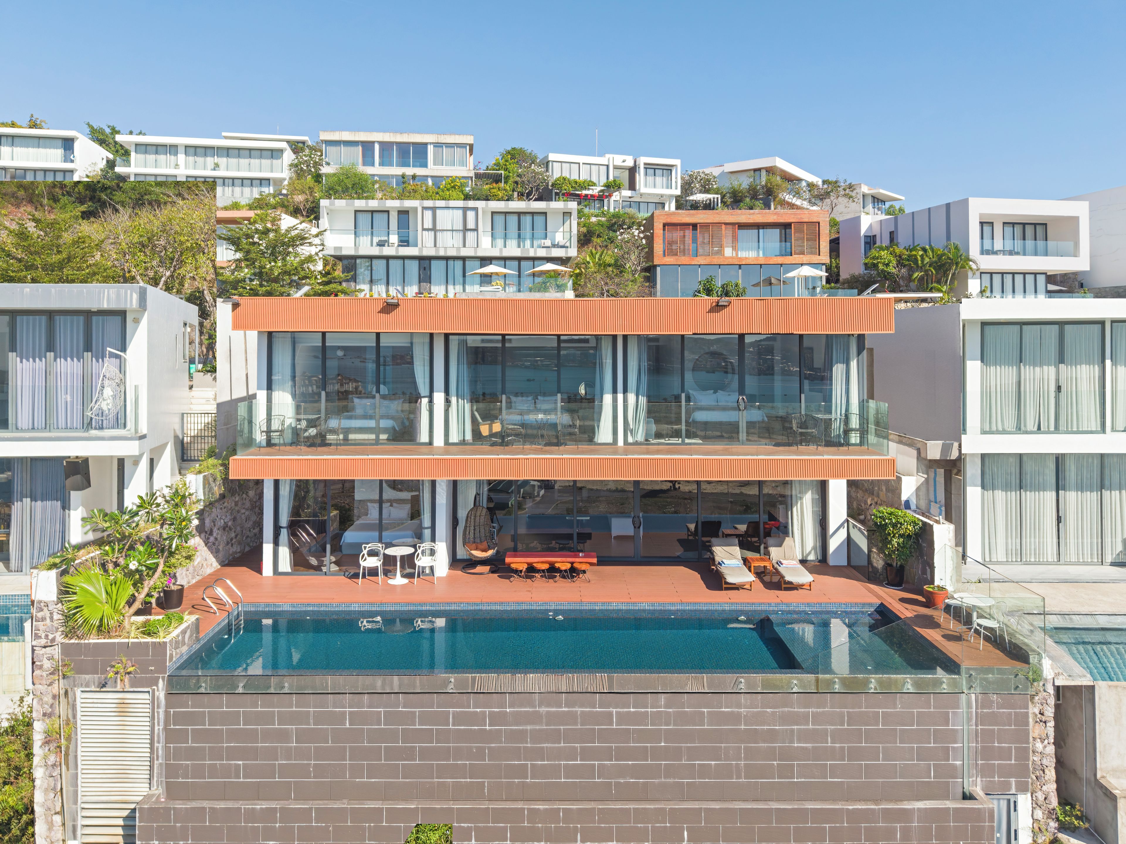 A modern two-story house with a rooftop pool, outdoor seating, and a view of neighboring buildings.