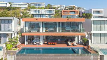 A modern two-story house with a rooftop pool, outdoor seating, and a view of neighboring buildings.