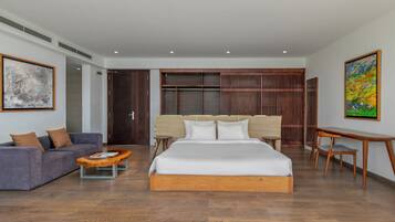 A modern hotel room with a large bed, a sofa, a small table, and a desk.