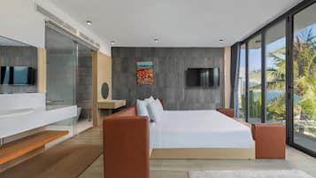 A modern bedroom with a large bed, a TV, and a view of palm trees.